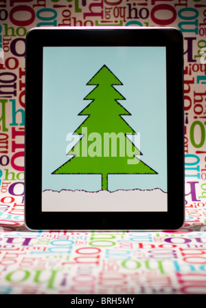 Ein iPad mit einem Bild eines Baumes (Ich habe den Baum selbst) mit "Ho Ho Ho" wrapping Paper Background. Stockfoto