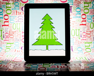 Ein iPad mit einem Bild eines Baumes (Ich habe den Baum selbst) mit "Ho Ho Ho" wrapping Paper Background. Stockfoto