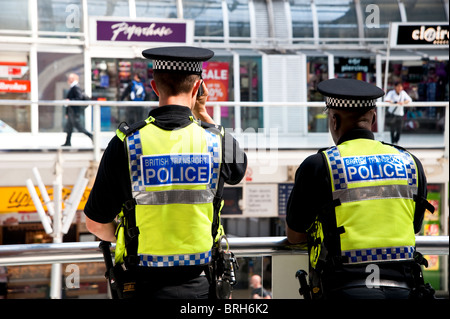 Zwei British Transport Police Officers sehen Pendler unten als sie durchlaufen der Bahnhof Liverpool Street in der City of London. Stockfoto