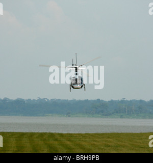 Ein Eurocopter AS350-B2 (Ecureuil/Eichhörnchen) im Flug über eine Start-und Landebahn auf einer Insel im Viktoriasee, Uganda Stockfoto