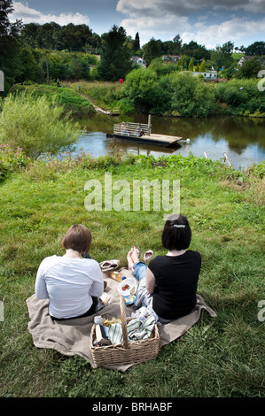 Zwei Personen haben ein Picknick beobachten Hampton Loade Fähre überqueren den Fluss Severn in der Nähe von Bridgnorth, Shropshire, UK Stockfoto