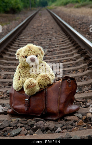 Teddybär und Koffer auf Bahngleisen Stockfoto