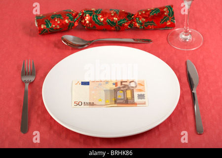 50 Euro-Banknote auf einem weißen Teller auf roten Tischdecke Gedeck und Christmas cracker Stockfoto