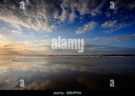 Spiegelt sich der Himmel im nassen Sand am Brancaster Strand an der Küste von North Norfok. Stockfoto