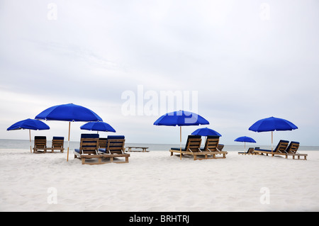 Sonnenschirme und Liegestühle am einsamen Strand. Stockfoto