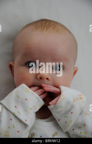 3 Monate altes Babymädchen saugen Finger schwarz & weiß mit blauen Augen Stockfoto