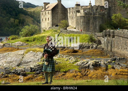 Eine Piper in traditioneller Tracht außerhalb Eilean Donan Castle, Dornie, Schottland Stockfoto