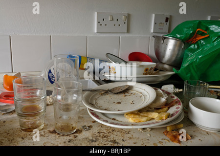 Sehr schmutziges Geschirr auf eine schmutzige Küchenarbeitsplatte Stockfoto