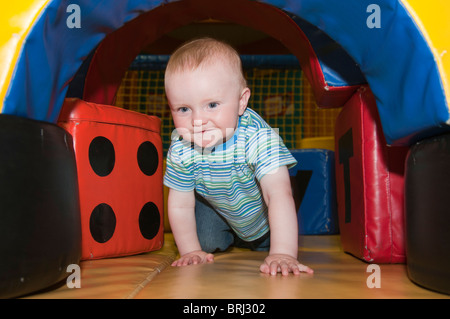 1 Jahr altes Baby durch einen Spiel-Tunnel kriechen Stockfoto