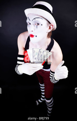 lustige Mime in weiße Mütze und Handschuhe, hält einen Stapel von hundert-Dollar-Scheine Stockfoto