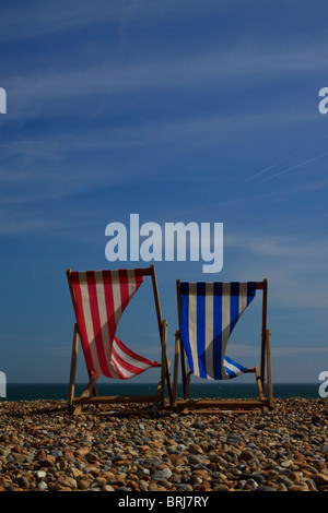 Zwei Liegestühle am Strand von Brighton vor einem strahlend blauen Himmel an einem windigen Tag Stockfoto