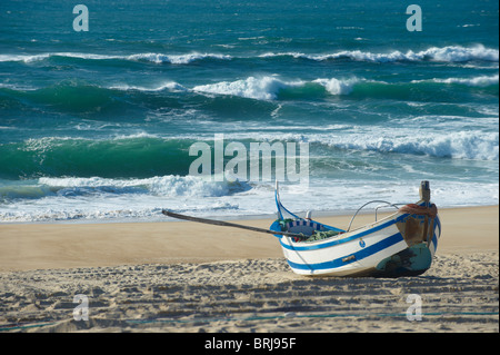 Blauen und weißen traditionellen portugiesischen hölzernen Fischerboot mit dem Atlantischen Ozean als Hintergrund in Praia de Mira, Portugal Stockfoto