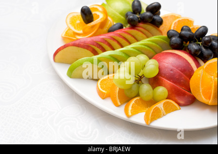 Schneiden Sie Äpfel und Orangen mit Trauben auf ovalen Platte, flachen DOF Stockfoto