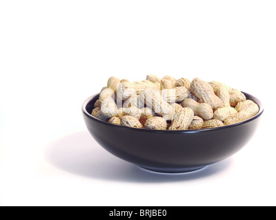 Schwarze Schale mit ungeschälte Erdnüsse, isoliert auf weiss. Stockfoto