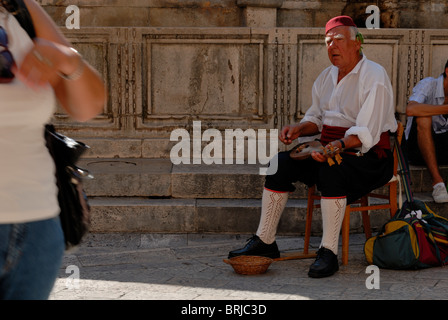 Ein Alter Mann in Tracht, die Mandoline zu spielen, im Schatten der großen Onofrio Brunnen. Placa, Dubrovnik, Dalmatien, Kroatien... Stockfoto