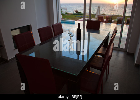 Esstisch mit Flasche Wein und zwei Gläser Wein mit Blick auf den mediterranen Sonnenuntergang Stockfoto
