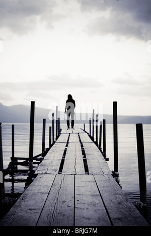 Mädchen stehen am Ende eines Piers auf See auf der Suche nach außen. Stockfoto