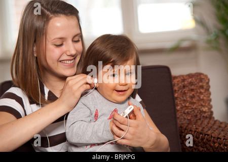 Teenager-Mädchen mit Baby Boy anhören von MP3-Player Stockfoto