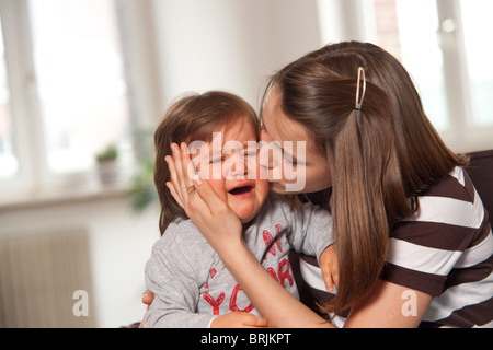 Teenager-Mädchen küssen schreiendes Baby Boy Stockfoto