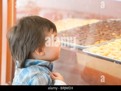 Jungen im Bäckerei-Fenster suchen Stockfoto