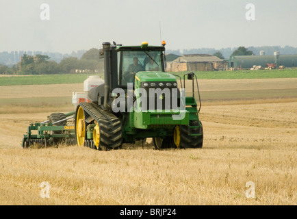 John Deere Kautschuk verfolgt Traktor in einem kürzlich geernteten Maisfeld bereit zum Pflügen der Erde aufbrechen Stockfoto