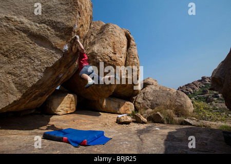 Kaukasische Männer Kletterrose schneiden lose auf einem Highball-Boulder in Hampi, Indien. Stockfoto