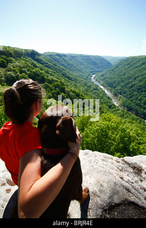 Frau und ihr Hund genießen Sie den Ausblick von einer hohen Klippe. Stockfoto