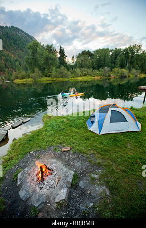 Junge Erwachsene paar camping mit einem Lager Feuer und Kajaks an einem schönen Sommerabend. Stockfoto