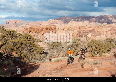 Zwei junge Männer fahren ihre Fahrräder über den Slickrock am Amasa Rücken Trail in Moab, UT Stockfoto