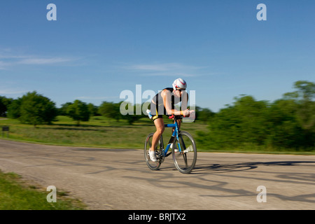 Ein männlicher Athlet Training für einen Triathlon an einem See mit dem Fahrrad. Stockfoto