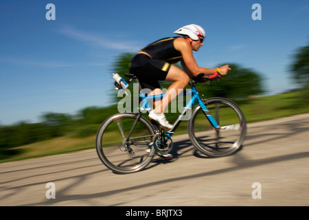 Ein männlicher Athlet Training für einen Triathlon an einem See mit dem Fahrrad. Stockfoto