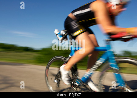 Ein männlicher Athlet Training für einen Triathlon an einem See mit dem Fahrrad. Stockfoto