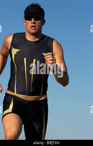 Eine männliche Athlet läuft beim Training für einen Triathlon an einem See. Stockfoto