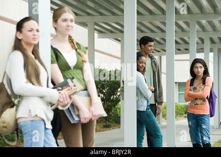 Schülerinnen und Schüler nach der Schule unter überdachten Gehweg für Bus warten Stockfoto