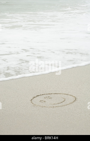 Smiley-Gesicht gezeichnet im Sand am Strand Stockfoto