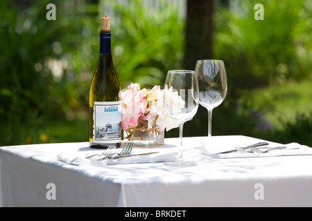 Weingläser und Weinflasche auf Tisch mit weißen Tischdecken außerhalb Stockfoto