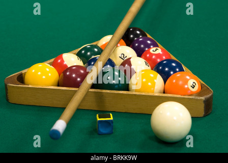 farbige Kugeln mit Zahlen in dreieckigen Rahmen, Kreide, weiße Kugel und Cue auf grünen Billardtisch Stockfoto