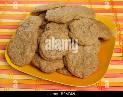 kleine Stapel von Gluten freie Schokoladenkekse auf einem gelben und orangefarbenen Hintergrund Stockfoto