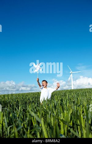 Junge läuft im Feld mit Windkraftanlage Stockfoto