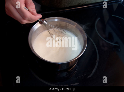 Schwenken der Creme wird gerührt über Kopf durch die Hand einer Frau Stockfoto