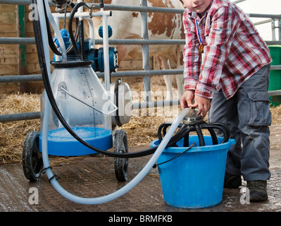 Junge Melken Reinigungsgeräte in Scheune Stockfoto