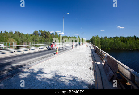 Biker, die über eine Straßenbrücke, wo die Hälfte des Decks ist unter Reparaturen und Asphalt wurde, abgestreift, Finnland Stockfoto