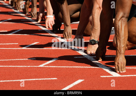 männlichen Sprinter richten Sie ihre Hände auf die Startlinie auf Leichtathletik-Veranstaltung Stockfoto