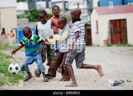 Gruppe von jungen spielen Fußball auf der Straße in Nompumulelo township Stockfoto