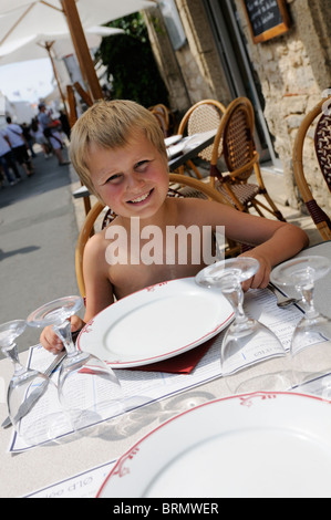 Stock Foto von einem 10 Jahre alten Jungen sitzen an einem Tisch im Restaurant warten um bedient zu werden. Stockfoto