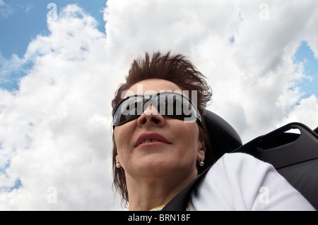 Reife, dunkle Haare Frauen mit großen Sonnenbrille geniessen Sie eine Fahrt im Cabrio, Skyline-Portrait, Nahaufnahme, London, England, EU Stockfoto