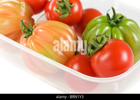 Rote und grüne Tomaten auf einer Kunststoff-Box isoliert Stockfoto