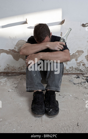 Alkoholiker, die auf dem Boden sitzend Stockfoto