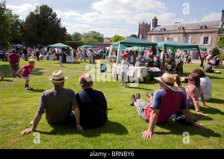 Eine Familie sitzt auf dem Rasen beobachten die jährlichen Sommer Charminster Fete in Dorset Dorf von Charminster. DAVID MANSELL Stockfoto