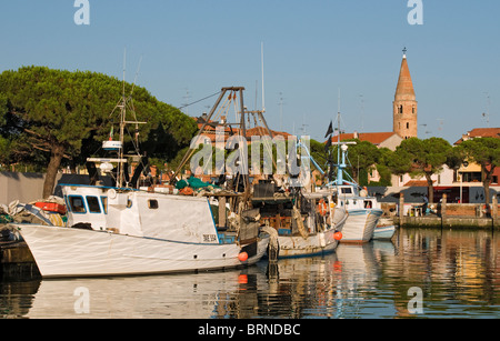 Fischerboote und Yachten auf dem Wasser Kanal mit Dom Glockenturm (Campanile) im Hintergrund, Caorle, Venetien, Italien Stockfoto